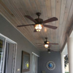 A fan with the lights on in the patio of a house