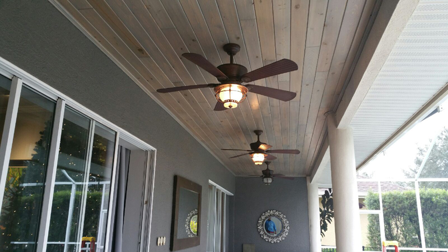 A fan with the lights on in the patio of a house