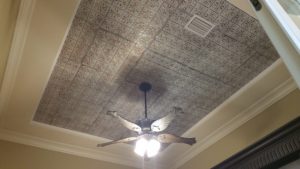 A ceiling with a grey floral pattern and a fan