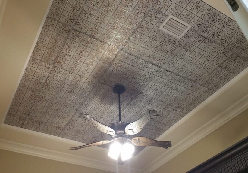 A ceiling with a grey floral pattern and a fan